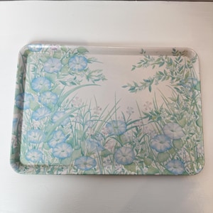 May include: Rectangular serving tray with a floral design. The tray has a light background with a pattern of blue morning glories, green leaves, and delicate white flowers. The edges are rounded.