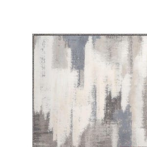 May include: Abstract area rug with a textured design. The rug features a blend of white, gray, and blue hues, creating a modern, artistic aesthetic. The edges are finished with a dark border.