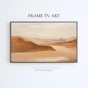 May include: A framed landscape painting depicting a desert scene with rolling sand dunes in shades of tan and brown. The artwork is labeled "FRAME TV ART" at the top and "@VelvetDisplay" at the bottom.