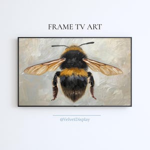 May include: A framed artwork featuring a detailed painting of a bumblebee with outstretched wings. The bee has a black and yellow body, with translucent wings. The artwork is set against a textured, neutral background. Text at the top reads "FRAME TV ART".