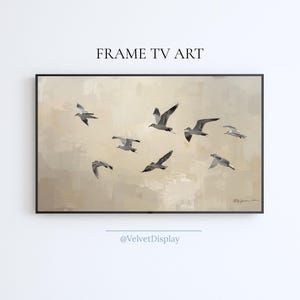Puede incluir: Impresión artística digital enmarcada que representa una bandada de gaviotas en vuelo sobre un fondo neutro y texturizado. La obra de arte está etiquetada como "FRAME TV ART" e incluye el identificador de redes sociales @VelvetDisplay.
