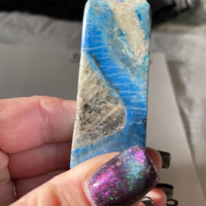 May include: A blue and white crystal point with a pointed tip. The crystal has a swirling pattern of blue and white.