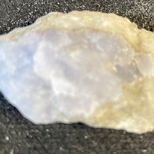 May include: A light purple and white rock with a rough, irregular shape.