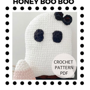 May include: Crochet pattern PDF for a white ghost with black eyes and a brown bow. The ghost is sitting on a pink and white crocheted base.