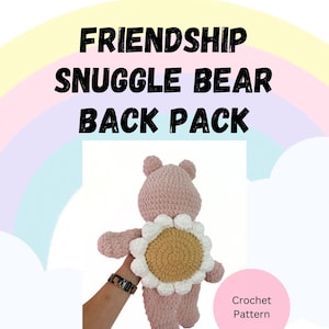 Può includere: Orso rosa all'uncinetto con uno zaino a forma di fiore all'uncinetto bianco e marrone. Il testo "Friendship Snuggle Bear Back Pack" e "Crochet Pattern" è visibile nell'immagine.