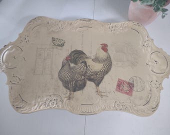 Può includere: Un vassoio da portata rettangolare color crema con bordi smerlati decorati e una finitura anticata. Il centro presenta un'illustrazione grafica di un gallo e una gallina, accentuata da tipografia sbiadita, un francobollo rosso e timbri postali.