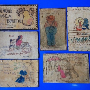 May include: Six vintage postcards with hand-drawn illustrations and handwritten messages. The postcards are made of leather and have a distressed look. The illustrations include a pear, a man in overalls, two people sitting on a bench, a person driving a car, a couple walking in the rain, and a couple under an umbrella.