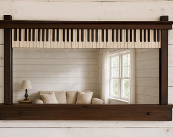 May include: A rectangular mirror with a dark brown wooden frame. The top of the frame features a piano keyboard design with black and off-white keys. The mirror reflects a room with a sofa, lamp, and window.