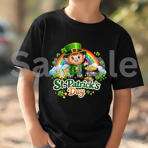 Puede incluir: Camiseta negra con un diseño del Día de San Patricio. El gráfico incluye un duende, un arcoíris, una olla de oro, una herradura y el texto "St. Patrick's Day". El diseño está rodeado de tréboles y estrellas.