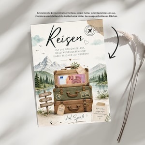 Pu&ograve; includere: Una carta rettangolare con una pila di tre valigie in stile vintage davanti a un paesaggio di montagne e un lago. Il testo recita Reisen, ist die sch&ouml;nste art, geld auszugeben und dabei reicher zu werden, e include una banconota da 10 euro nella valigia superiore. Un cartello in legno riporta la scritta Reisen macht gl&uuml;cklich.