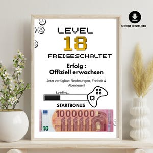 Könnte beinhalten: Ein gerahmter Druck mit dem Text "LEVEL 18 FREIGESCHALTET" in Schwarz und Gold. Darunter eine Grafik eines Videospiel-Controllers und eines Ladebalkens. Unten auf dem Druck befindet sich ein Zehn-Euro-Schein.