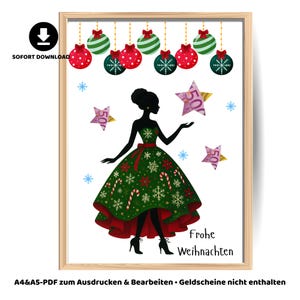 May include: A framed Christmas-themed print featuring a silhouette of a woman in a green and red dress adorned with snowflakes and candy canes. The print includes hanging ornaments, star-shaped money, and the text "Frohe Weihnachten".