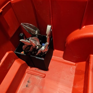 Puede incluir: Una caja de herramientas de plástico roja con un organizador de herramientas negro que contiene varias herramientas de metal. El texto "Packout / Tools NOT Included" es visible en la parte inferior de la imagen.