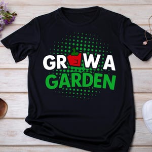 以下が含まれることがあります： 「GROW A GARDEN」の文字が白と緑で描かれた黒いTシャツ。赤いパプリカのグラフィックが特徴です。デザインにはテキストの周りに緑色のドットが施され、遊び心のある外観になっています。ガーデニング愛好家向けのカジュアルなTシャツです。
