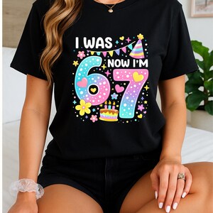 Może przedstawiać: Czarny t-shirt z napisem "I WAS 6, NOW I'M 7" w kolorowej, zabawnej czcionce. Projekt zawiera duże cyfry 6 i 7, serca, kwiaty, tort urodzinowy i czapeczkę urodzinową, idealny na urodziny.