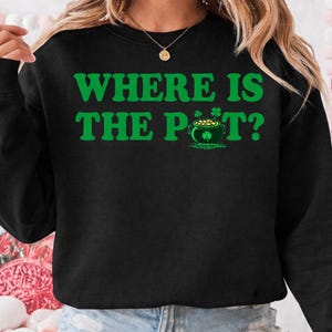 May include: Black sweatshirt with the text "WHERE IS THE POT?" in green. The design includes a green pot of gold and shamrocks, perfect for St. Patrick's Day. The sweatshirt is a casual, comfortable style.