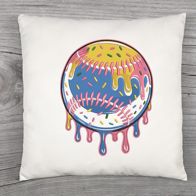 Puede incluir: Coj&iacute;n cuadrado blanco con un dise&ntilde;o de b&eacute;isbol con un toque &uacute;nico. La pelota es azul con costuras rosas y est&aacute; cubierta con glaseado amarillo y rosa, con chispas y glaseado goteando. Un acento decorativo divertido.