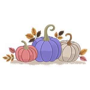 Pode incluir: Um desenho bordado com três abóboras em tons de rosa, roxo e creme. As abóboras são rodeadas por folhas de outono em tons de castanho, laranja e rosa, criando um tema de colheita de outono.