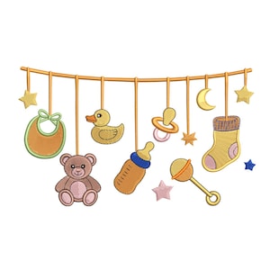 Puede incluir: Un conjunto bordado de artículos para bebés, que incluye un babero, un osito de peluche, un pato, un chupete, un biberón, un sonajero, un calcetín, estrellas y una luna creciente. Colgados de una barra dorada horizontal.