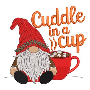 May include: A whimsical illustration features a gnome with a red hat and a long white beard, sitting next to a red mug of hot chocolate with marshmallows. The text "Cuddle in a Cup" is written in orange script above the mug. The image is set against a white background.
