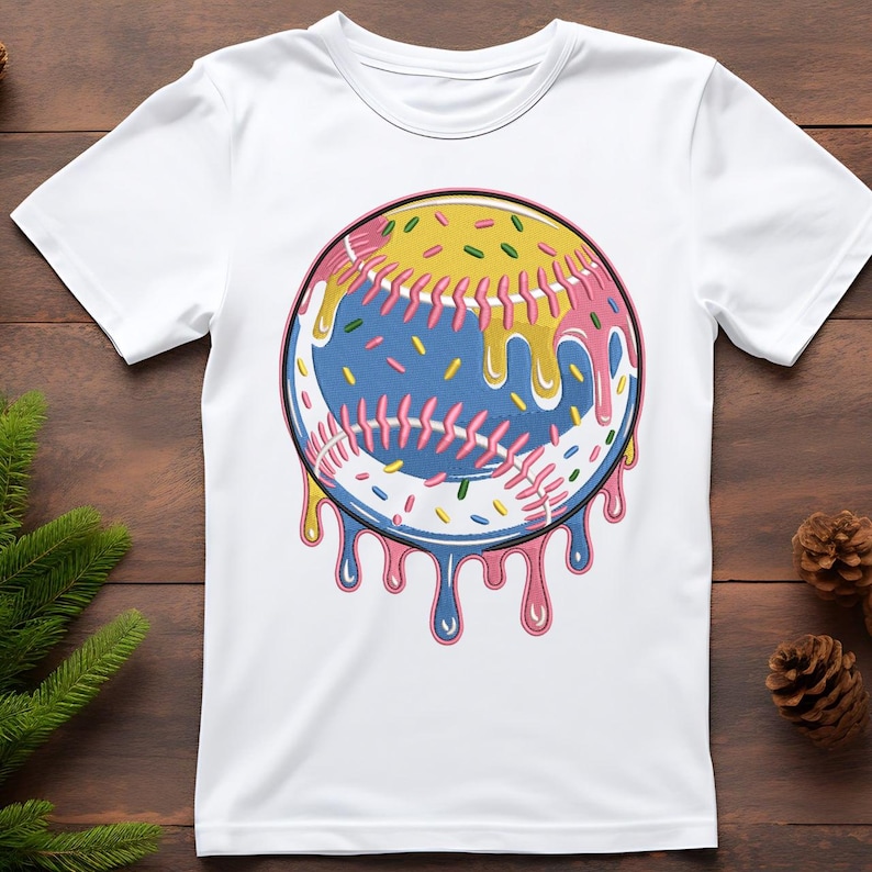 Puede incluir: Camiseta blanca con un gr&aacute;fico de b&eacute;isbol. La pelota de b&eacute;isbol es azul con costuras rosas, cubierta con glaseado amarillo y chispas de colores, con goteo rosa y azul. La camiseta est&aacute; hecha de un material suave. Dise&ntilde;o divertido.
