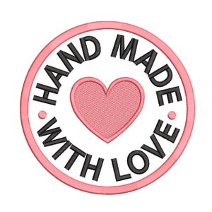 Peut inclure: Un écusson rond brodé en rose et blanc, avec l'inscription "HAND MADE WITH LOVE" en noir. Un cœur rose est au centre du motif.