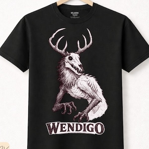 Puede incluir: Camiseta negra con una ilustración detallada de un Wendigo, una criatura mítica con cuernos y apariencia esquelética. La palabra "WENDIGO" está impresa en negrita, en una fuente estilizada debajo de la imagen. La camiseta es de algodón premium.