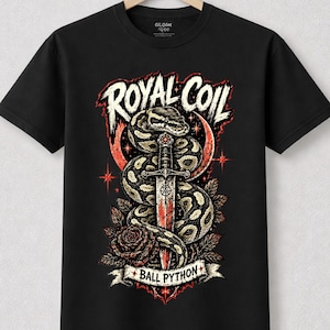 May include: A black short-sleeve t-shirt featuring a graphic print of a coiled snake wrapped around a sword, surrounded by roses and stars. The text ROYAL COIL appears above the snake, and the text BALL PYTHON is printed on a banner below.