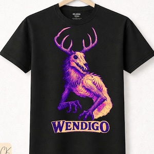 Puede incluir: Camiseta negra con un diseño de Wendigo morado y amarillo. El diseño incluye un cráneo de ciervo, cuernos y el cuerpo de una criatura. La palabra "WENDIGO" está impresa debajo. Hecha de algodón premium.
