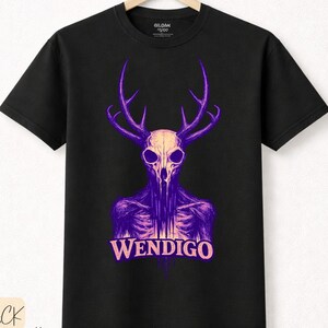 Puede incluir: Camiseta negra con un diseño Wendigo morado y blanco. El gráfico muestra una calavera con cuernos y la palabra "WENDIGO". La camiseta está hecha de algodón de primera calidad.