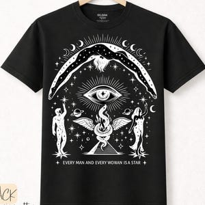 May include: Black t-shirt with a white graphic design featuring an eye, figures, and celestial elements. The text "EVERY MAN AND EVERY WOMAN IS A STAR" is printed below the design. The shirt also has the text "BLACK premium cotton".