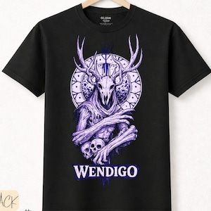 Puede incluir: Camiseta negra con un diseño morado de Wendigo. El diseño incluye una calavera con cuernos, un patrón circular y la palabra "WENDIGO" en blanco. Hecha de algodón premium.