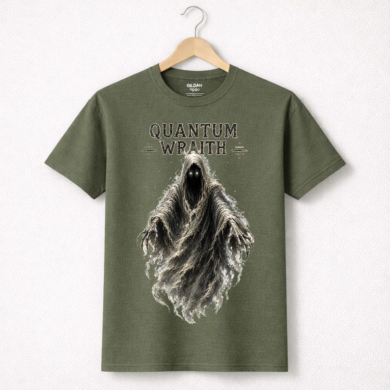 以下が含まれることがあります： オリーブグリーンのTシャツ。光る目を持つ幽霊のような姿と、ゴシック体の「QUANTUM WRAITH」の文字が描かれています。フードをかぶった幽霊が、煙のように流れる姿でデザインされています。