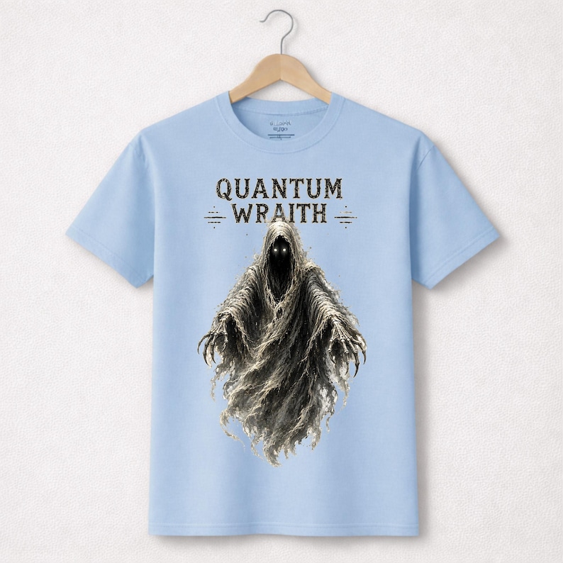以下が含まれることがあります： 「QUANTUM WRAITH」の文字と、光る目と伸びた爪を持つ幽霊のような人物の詳細なイラストが描かれた、水色のTシャツ。 デザインはTシャツの中央に配置されています。