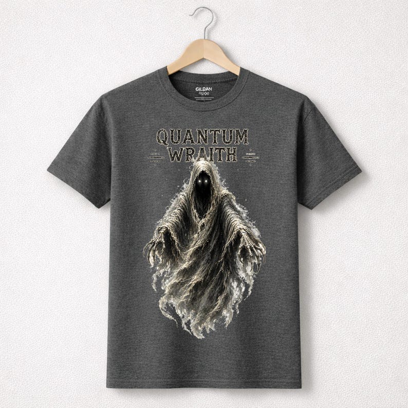 以下が含まれることがあります： 暗い灰色のTシャツ。 幽霊のような姿が描かれており、光る目とフード付きのマントが特徴です。「QUANTUM WRAITH」の文字がその上に印刷されています。 Tシャツは木製のハンガーに掛けられています。
