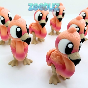 May include: A collection of 3D-printed flamingo figurines in shades of pink and peach. Each flamingo has large, expressive eyes, a black beak, and tan feet. The text "Zoodlez" is displayed in blue above the figurines.
