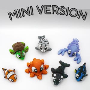 May include: A collection of miniature, colorful sea creature figurines, including a turtle, seal, lobster, octopus, clownfish, orca, and a blue and black fish. The text "MINI VERSION" is displayed above the figurines.
