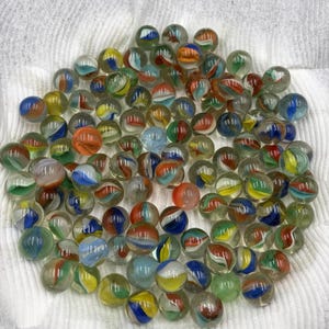 May include: A collection of colorful glass marbles. The marbles feature a variety of colors, including blue, red, yellow, and green, with swirled and striped patterns. The marbles are clear and appear to be vintage.