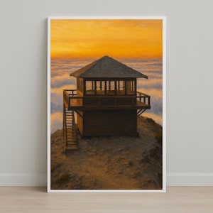 May include: A framed print of a wooden fire lookout tower perched atop a mountain, with a sunset sky in the background. The tower has a dark brown exterior, a small balcony, and a staircase leading up to it. The sky is a gradient of orange and yellow.