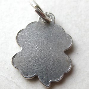 K&ouml;nnte beinhalten: Ein silberfarbener Kleeblatt-Anh&auml;nger mit strukturierter Oberfl&auml;che. Der Anh&auml;nger hat einen gewellten Rand und eine kleine Schlaufe oben zum Befestigen an einer Halskette oder einem Armband. Der Anh&auml;nger ist ein vierbl&auml;ttriges Kleeblatt.