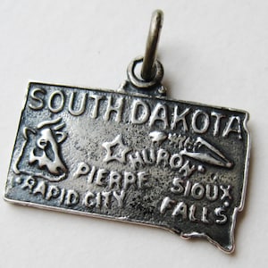 May include: A white ceramic mug with a black handle and the text "But First, Coffee" in a black, handwritten-style font. The mug is on a white surface.