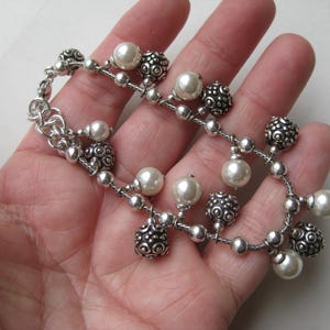 Puede incluir: Una pulsera plateada con un delicado dise&ntilde;o de cadena. La pulsera presenta una mezcla de cuentas redondas texturizadas y perlas de imitaci&oacute;n blancas cremosas. Un accesorio elegante.
