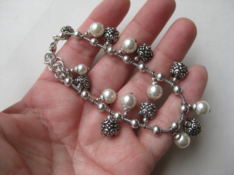 Puede incluir: Una pulsera plateada con un delicado dise&ntilde;o de cadena. La pulsera presenta una mezcla de cuentas redondas texturizadas y perlas de imitaci&oacute;n blancas cremosas. Un accesorio elegante.