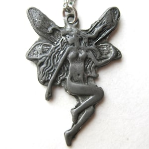 May include: A silver-colored pendant necklace featuring a fairy design. The fairy has long flowing hair and large wings. The pendant is suspended from a delicate silver chain. The fairy is in a graceful pose.
