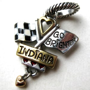 May include: A silver and gold charm with a racing theme. Features a checkered flag, a flag that says "GO BRIGHTON", and a banner that says "INDIANA". Includes a heart-shaped charm and a twisted silver ring.