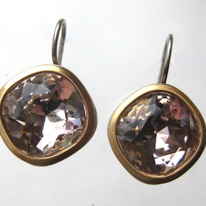 May include: A pair of drop earrings featuring square-shaped, faceted champagne-colored crystals set in smooth, matte gold-toned metal bezels. Each earring is attached to a simple, curved silver-toned metal hook for secure placement on the ear.