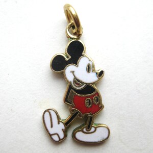 Puede incluir: Un charm dorado que representa a Mickey Mouse en un dise&ntilde;o colorido. El charm muestra a Mickey con su atuendo cl&aacute;sico: orejas negras, cara blanca, pantalones cortos rojos y zapatos amarillos. El charm est&aacute; dise&ntilde;ado con detalles de esmalte.
