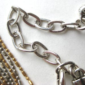 Puede incluir: Un collar de m&uacute;ltiples hilos con cuentas met&aacute;licas que alternan tonos dorados y plateados. El collar incluye una cadena extensora plateada con eslabones ovalados y un dije en forma de coraz&oacute;n al final, con un dise&ntilde;o de letra grabada en cursiva.