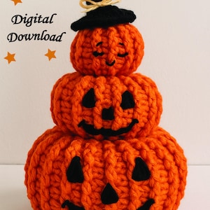 Op de afbeelding: Een handgemaakte, drielaagse oranje gehaakte pompoen met zwarte gezichtskenmerken en een zwarte heksenhoed. De bovenste pompoen heeft gesloten ogen, terwijl de andere grijnzende pompoengezichten hebben. De tekst "Digital Download" is zichtbaar.