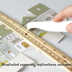 An illustration of hand assembling printable advent calendar houses